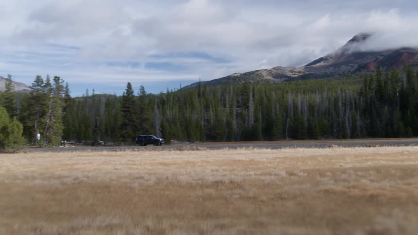 A vehicle drives by a mountain forest