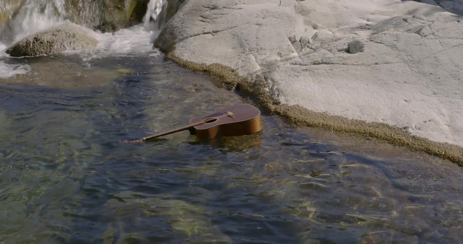 Guitar floats down a rocky stream