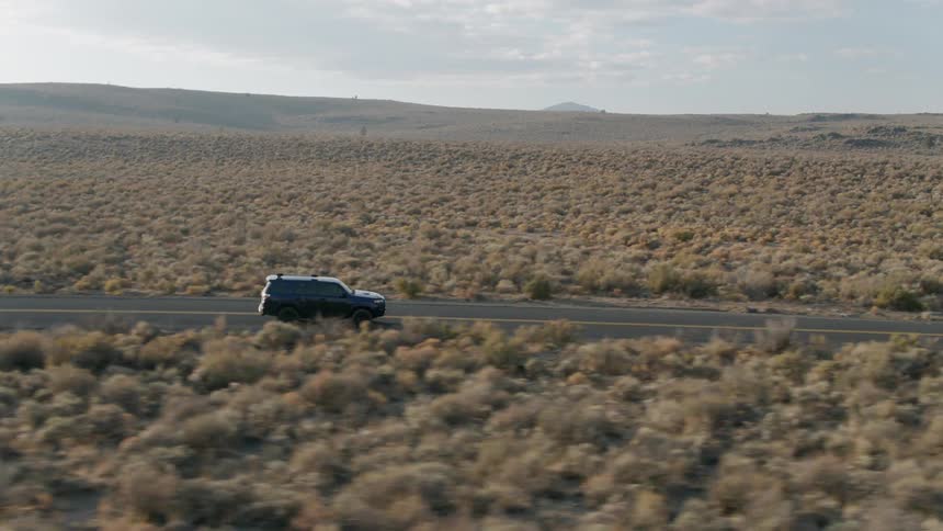 A vehicle drives in a rural desert