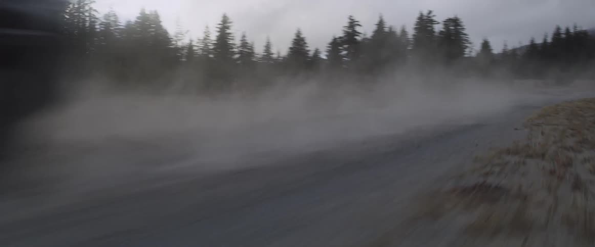 An suv is driving fast on a rural dirt road at dusk
