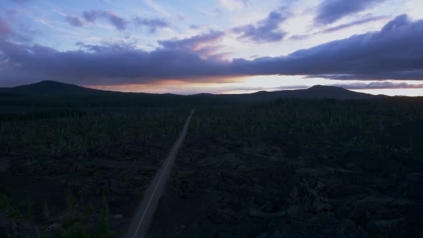 A lone road through hilly land at sunset