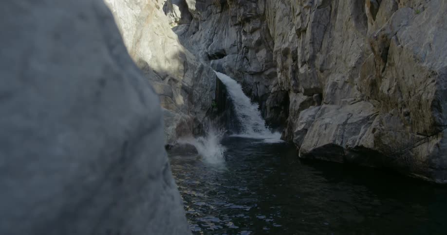 A man jumps from a cliff into water below fully clothed