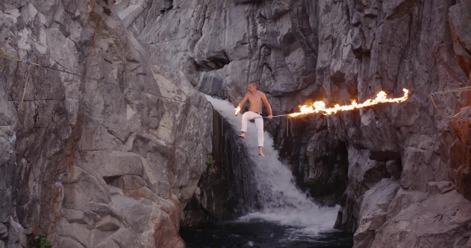 Man sits on a burning wire suspended between the cliffs