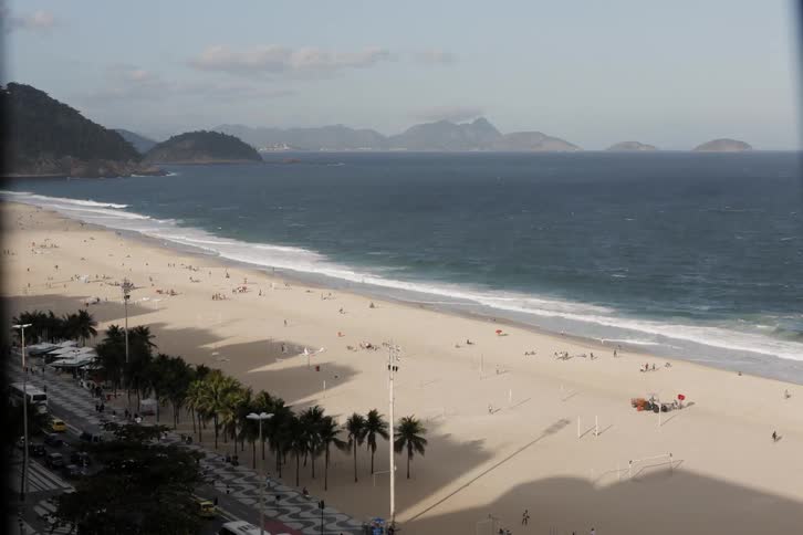 People swim and walk on a sandy beach