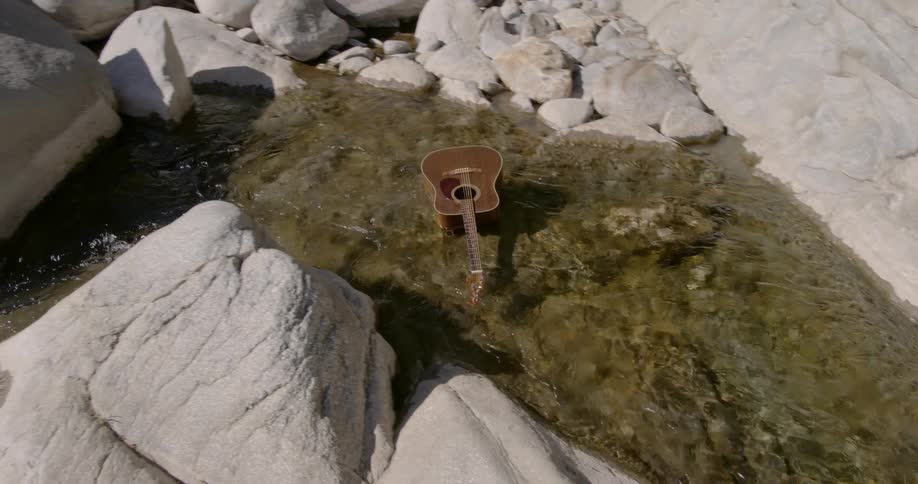 Guitar floats down a shallow rocky stream