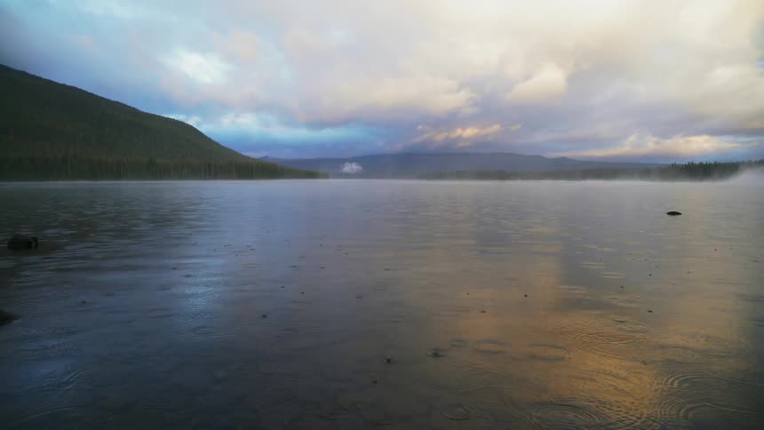 Rain drops fall onto flowing lake waters