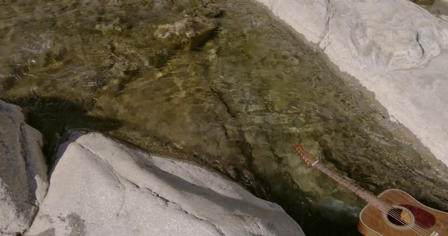 A guitar floats peacefully down a stream