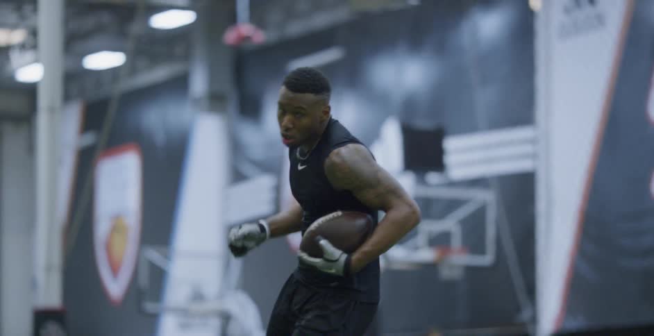 An athlete runs with a football indoors