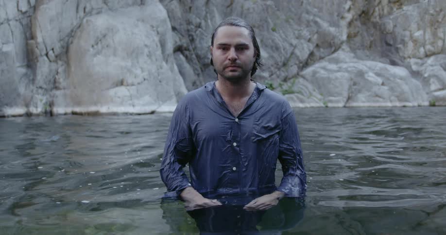 A clothed man stands in waist deep water