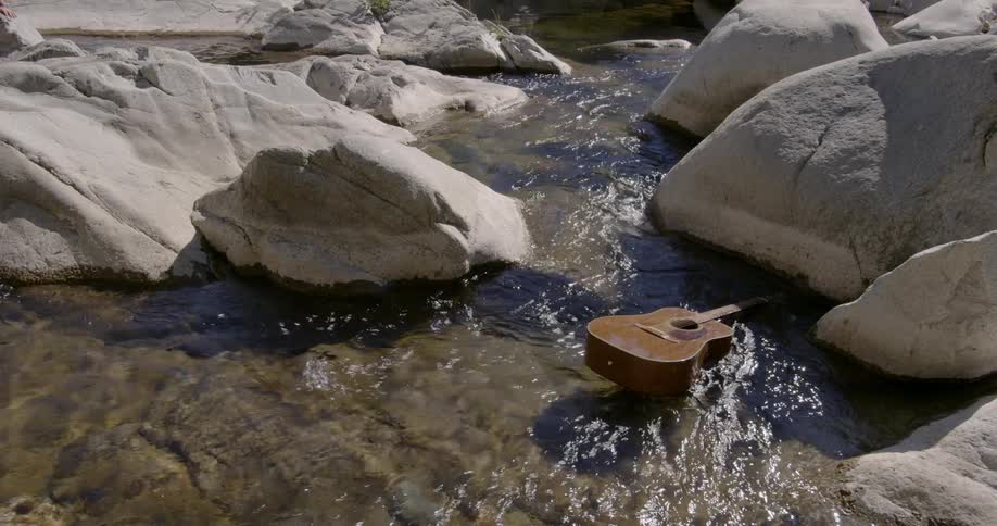 Guitar floats between the rocks down a creek