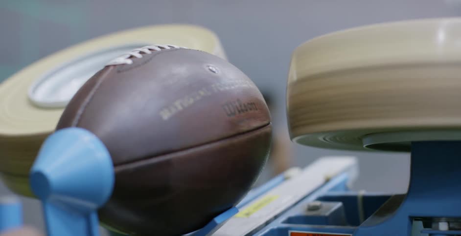 One person loads a football and launches it to another man who tries to catch it