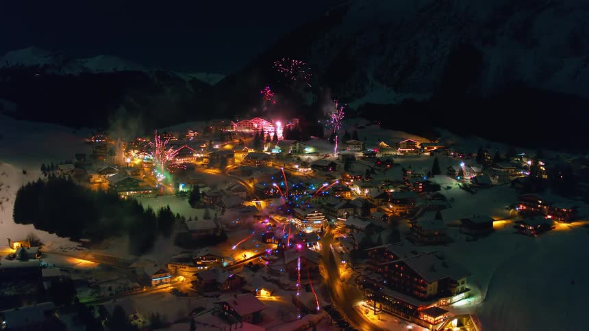 Fireworks explode over a small snow covered village