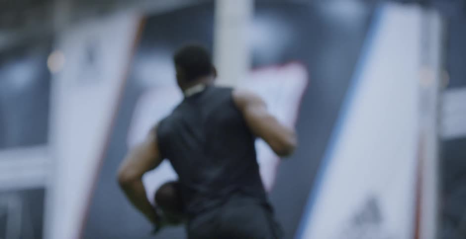 A man runs and catches a football at an indoor practice facility