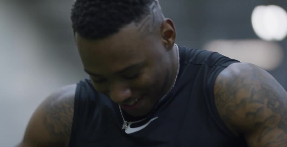 A male athlete is smiling and talking indoors