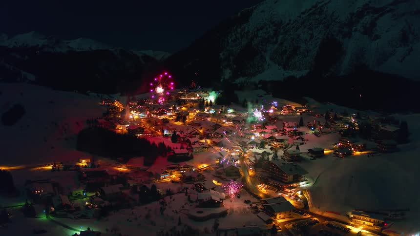 Fireworks explode over a snowy mountain village