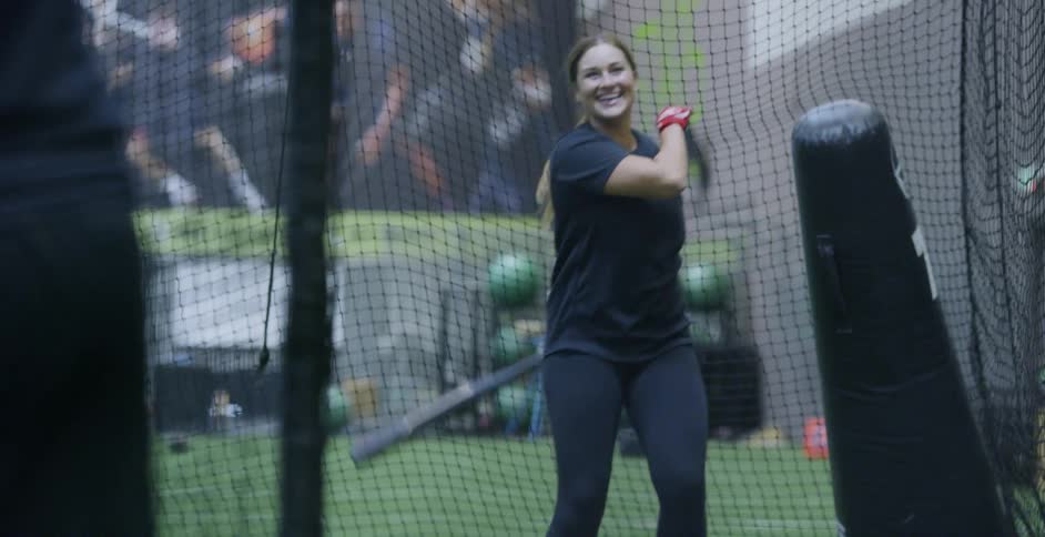 A baseball player practices hitting a ball with a bat