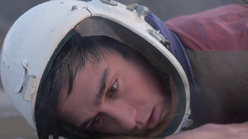 Person wearing helmet lying face down in water slowly gets up