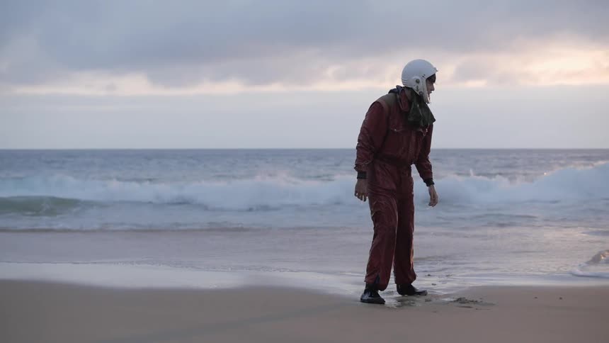 Man in astronaut suit emerges from the ocean