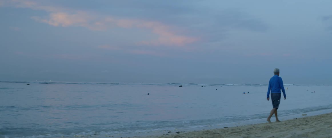 A man walks on the beach at sunset