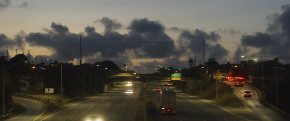 Clouds are drifting over a freeway at dusk