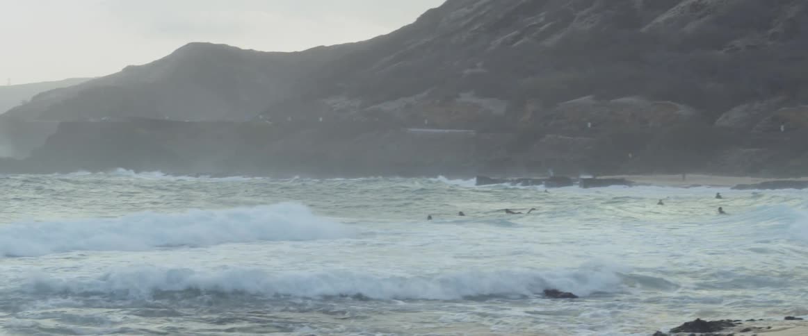 Surfers sit and lie on their surfboards in the ocean