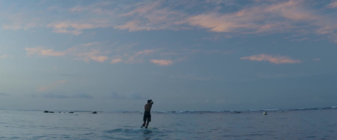 Man paddle boards on the ocean at sunset
