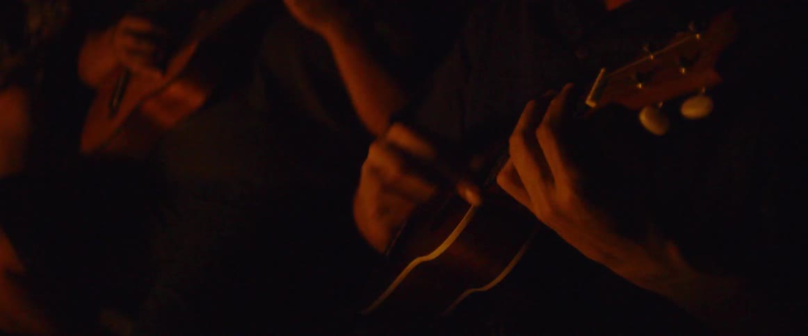 A man plays guitar next to a campfire