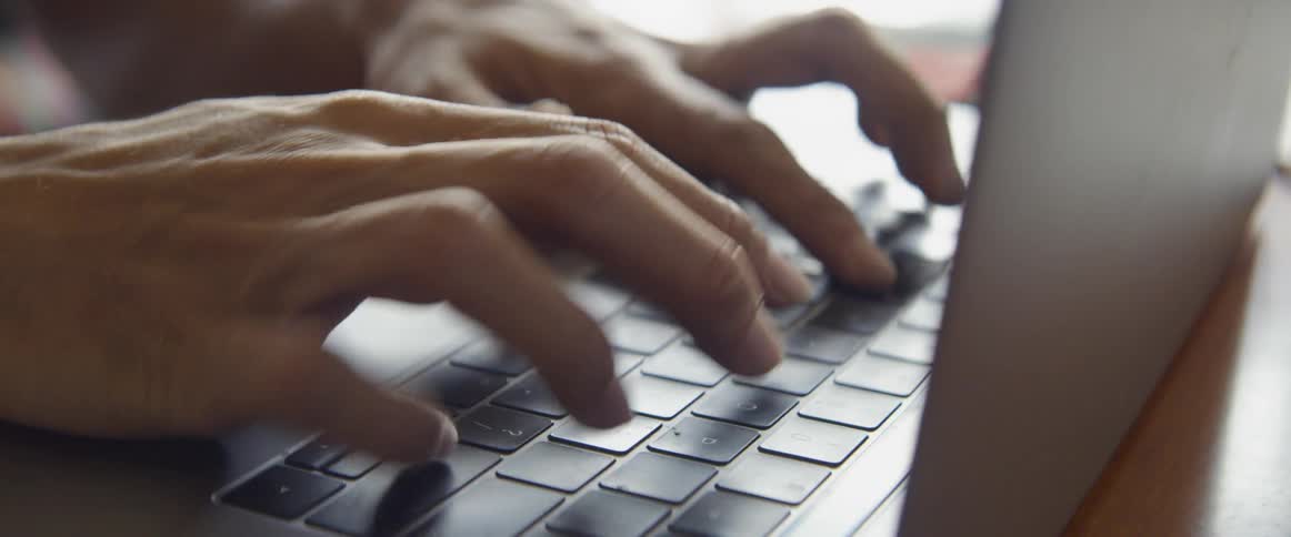 Hands typing on a laptop keyboard