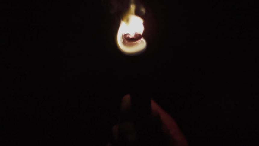 Hand holding a lit flare in a dark area