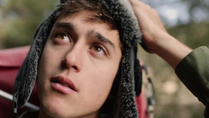 Man walks forward then removes his hat while looking up