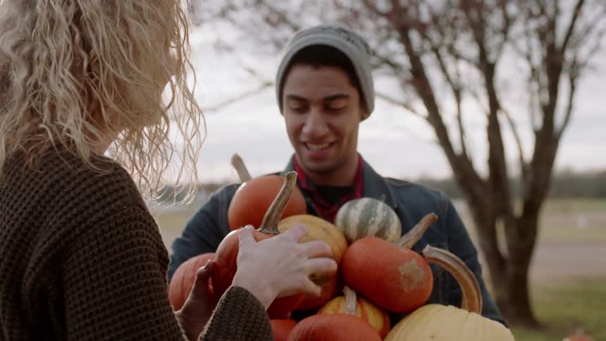 Woman loads a variety of pumpkins into a man's arms