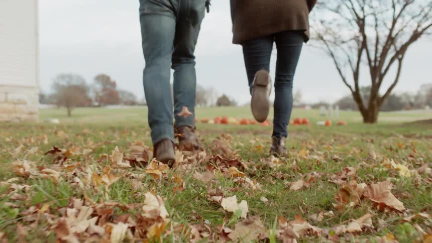 A man and woman run towards pumpkins set up in a field
