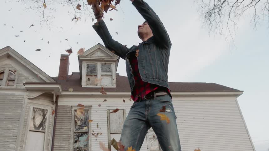 A couple are tossing autumn leaves into the air during the day