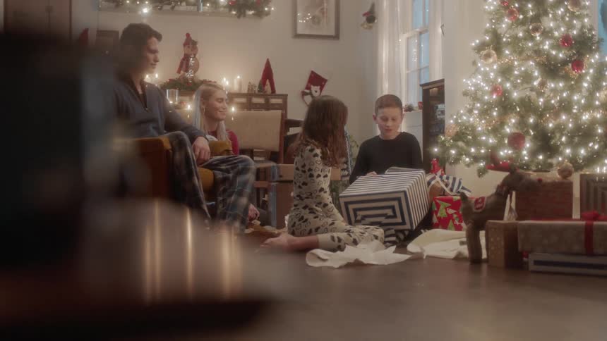 A family opens gifts next to a christmas tree