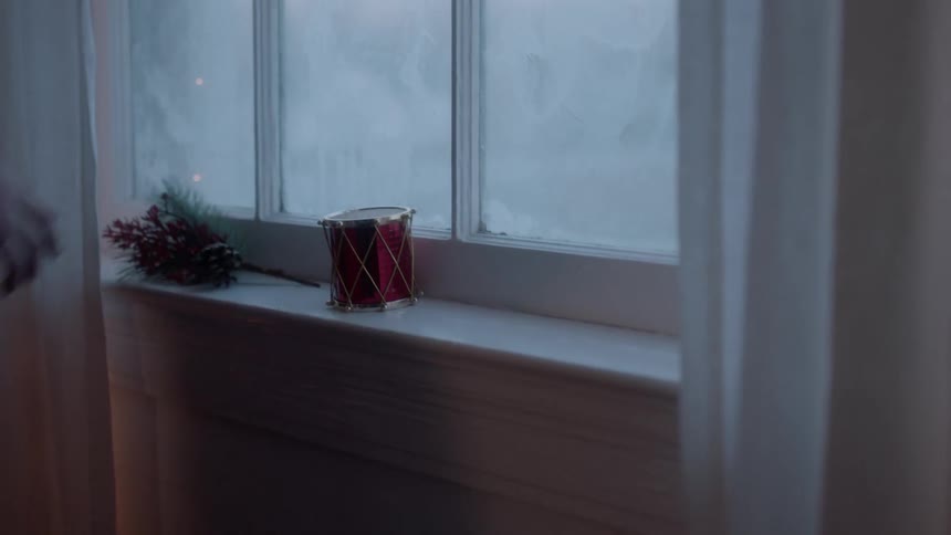 Girl puts christmas decorations on a window ledge
