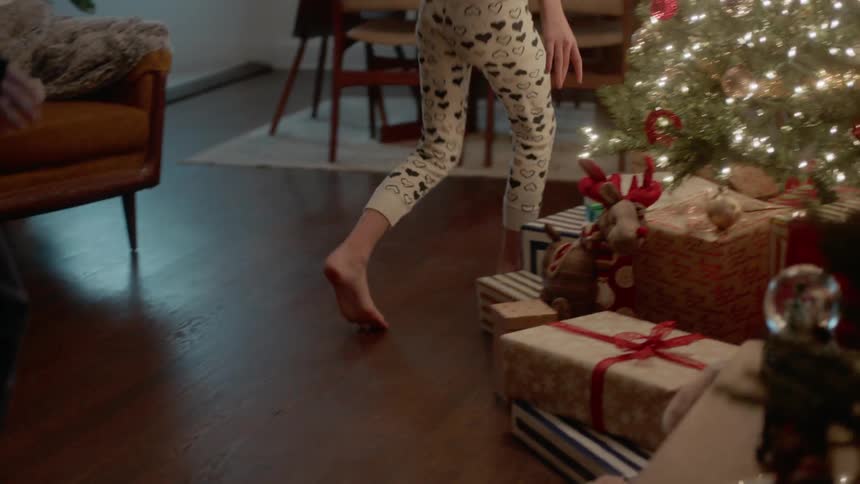 A family is excitedly running towards their christmas gifts on christmas morning