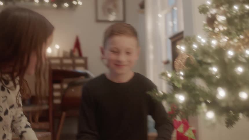 A family opens gifts next to a christmas tree