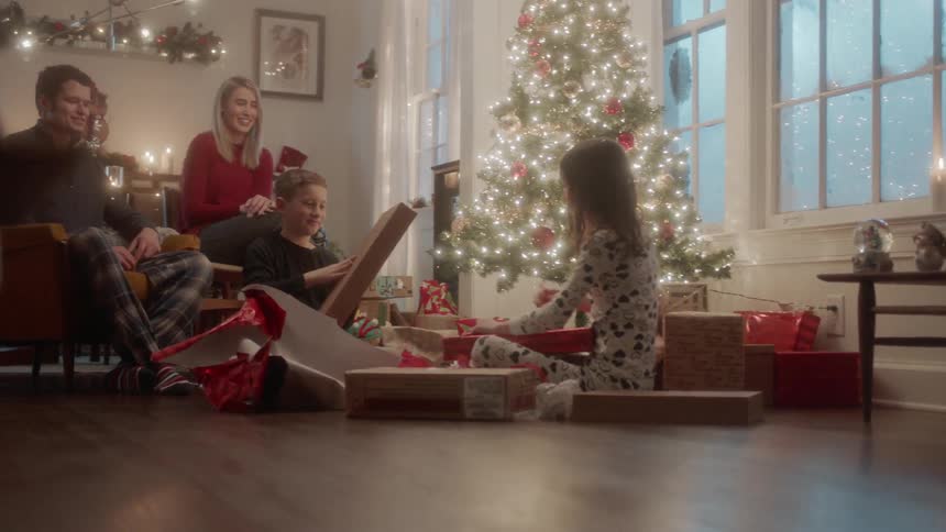 A family opens gifts next to a christmas tree