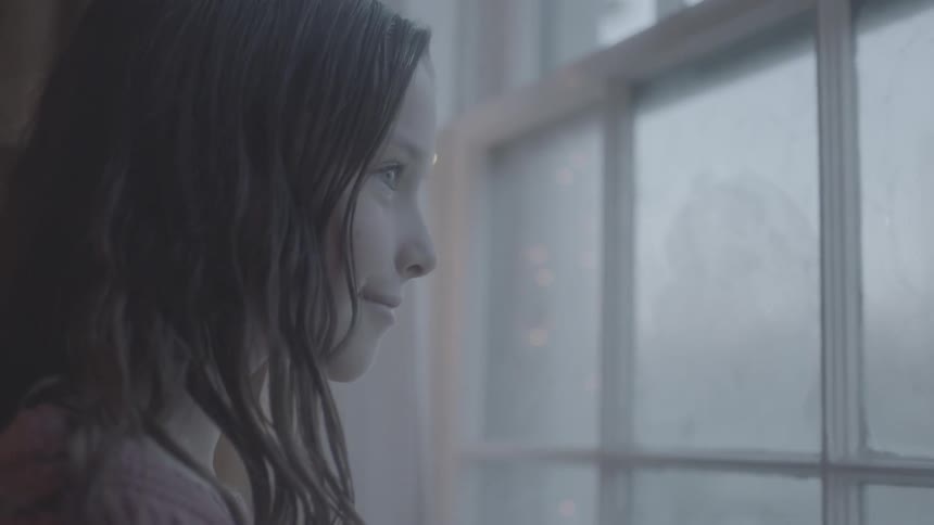 A girl smiles while looking out a window