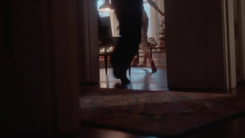 A boy and girl run into a living room on christmas