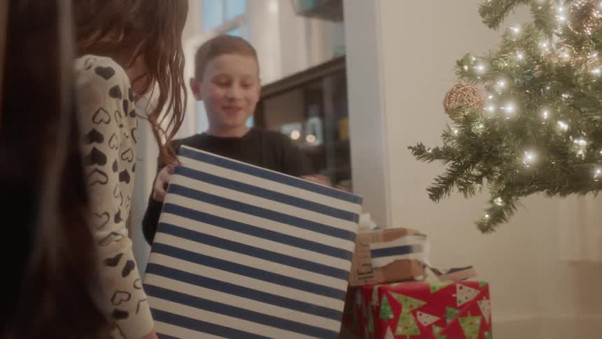A boy and girl open christmas presents