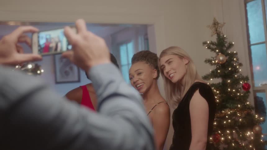 Women are photographed next to a christmas tree