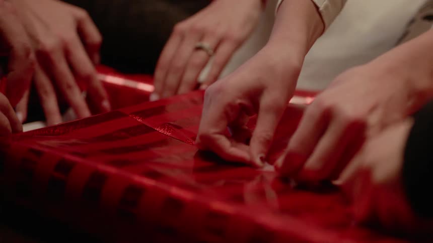 Multiple people wrap a single gift