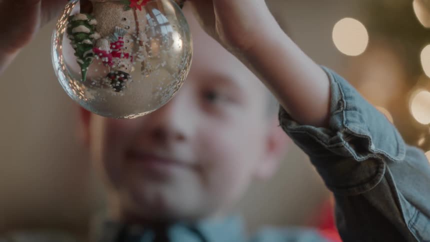 A boy holds a snow globe upside down