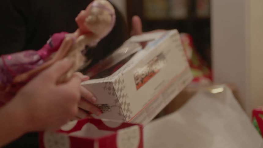 A girl holds and plays with the hair of a barbie doll