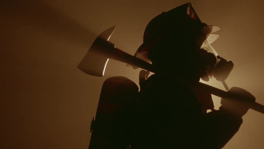A firefighter is wearing his uniform and holding an axe