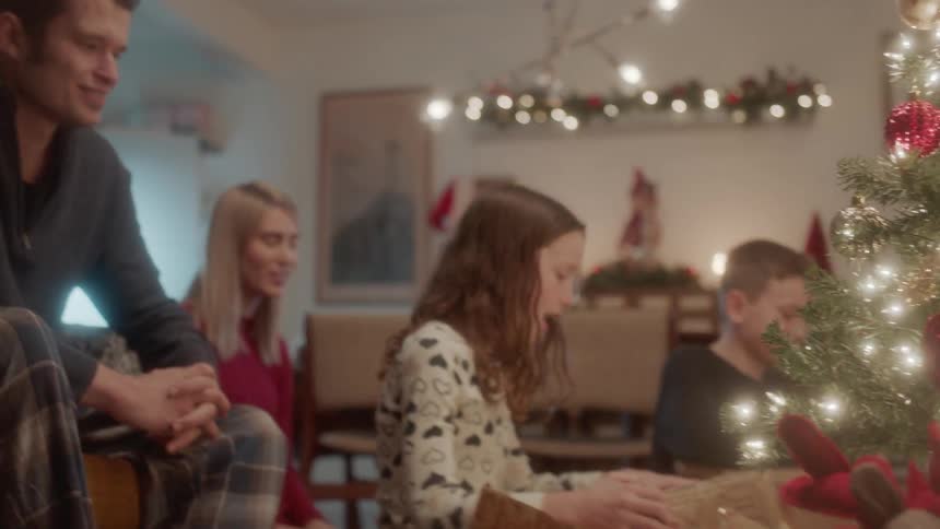 Parents watch their kids open presents on christmas day