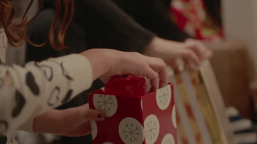 A couple sit and unwrap presents