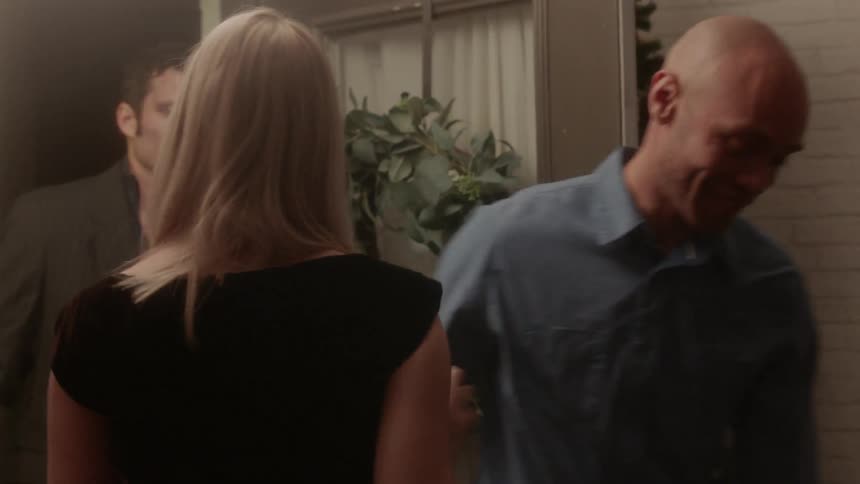 A woman opens the door and greets her guests with hugs