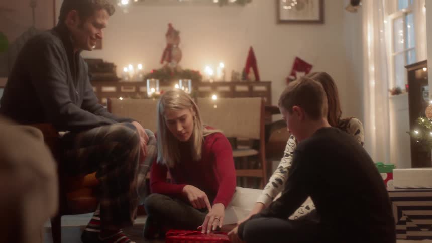Family wraps a christmas present on a living room floor